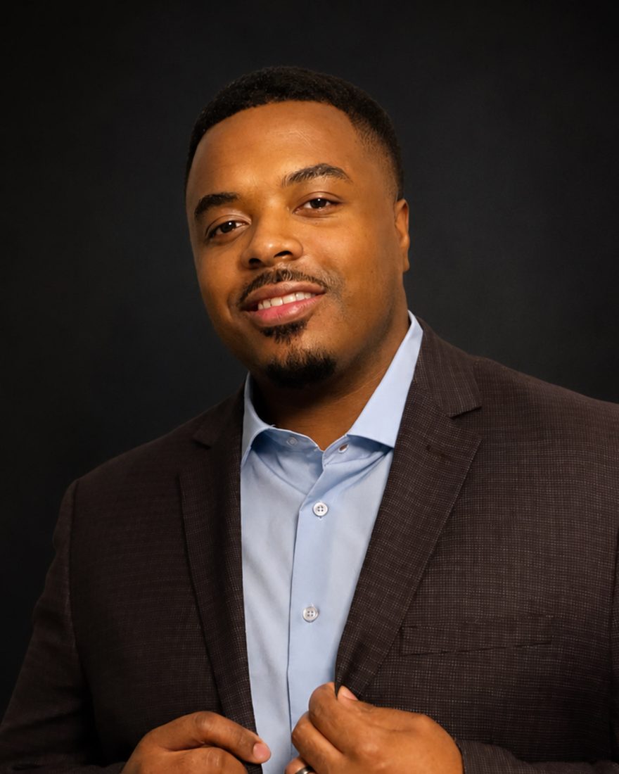 Darion Gatson, engineering leader, in a dark suit against a charcoal backdrop